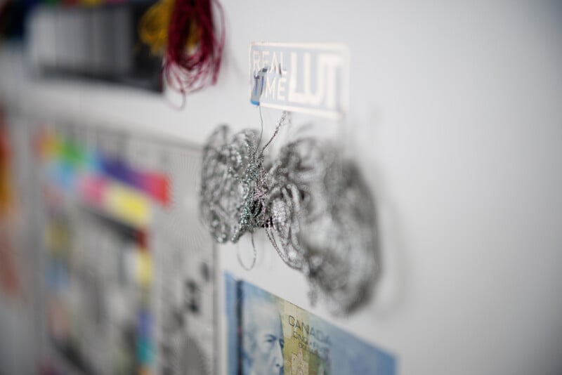 Blurry image of a bulletin board with a shiny wire ornament, a colorful grid, and currency note. There's also a partially visible label that reads "REAL TIME LUT." The focus is on the wire ornament in the foreground.