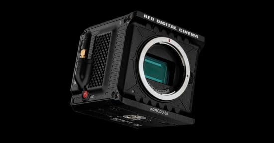A red komodo 6k digital cinema camera with a black body and a large lens mount, displayed against a dark background. the camera features prominent branding and a compact design.