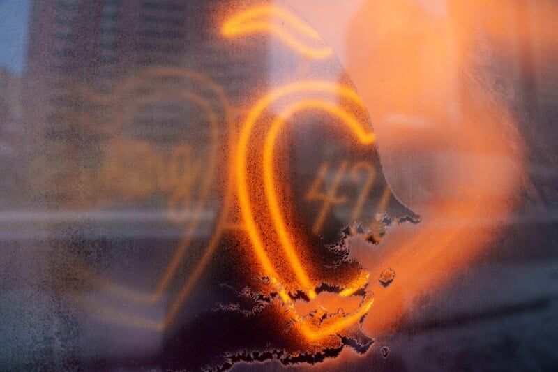 Foggy window with two heart shapes and the number "49" drawn on it. Orange light illuminates the scene from behind, creating a warm glow and leaving streaks on the glass.