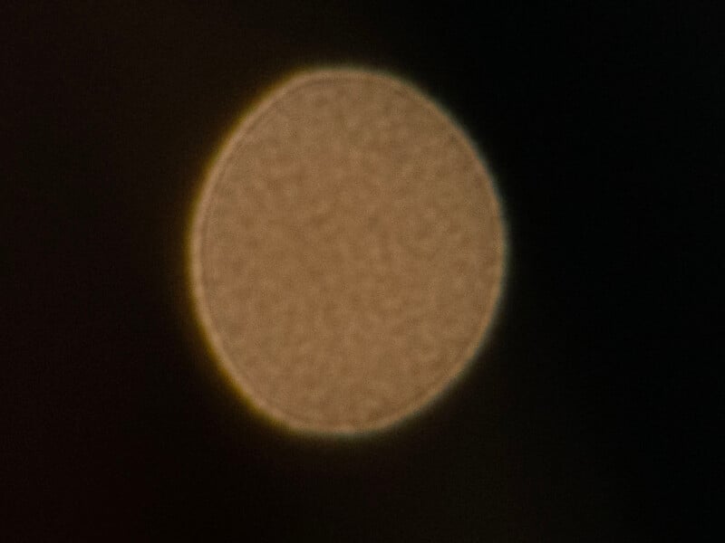 A blurred, circular light source appears against a dark background, creating a soft halo effect around its edges.