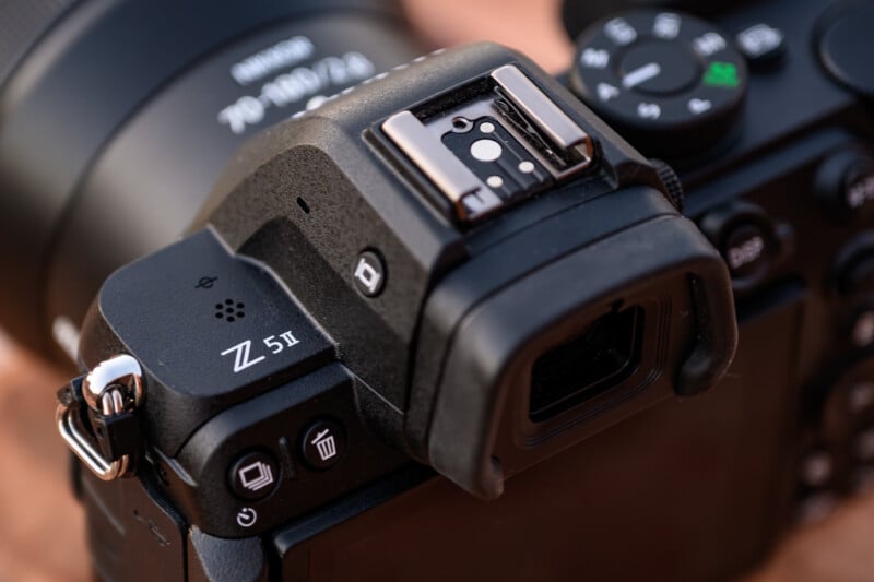 Close-up of the top section of a Nikon Z 5II camera, focusing on the electronic viewfinder, controls, and buttons. The camera's textured black finish and branding are visible, with a lens partially in view on the left.