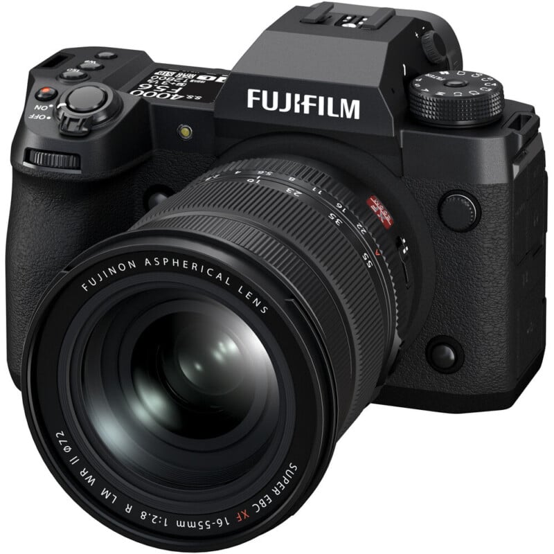 A black Fujifilm digital camera with a large Fujinon aspherical lens, featuring dials and buttons for controls. The camera has a textured grip and is angled slightly to show the front and side.