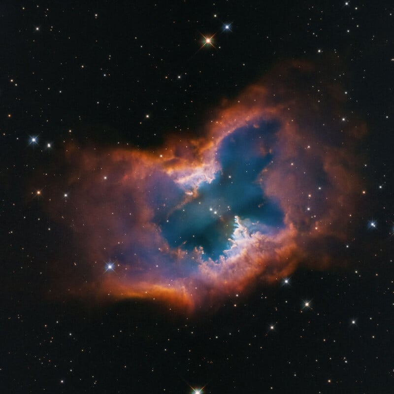 A colorful nebula with a butterfly-like shape glows in space, featuring blue, purple, and orange clouds surrounded by scattered stars against a dark background.