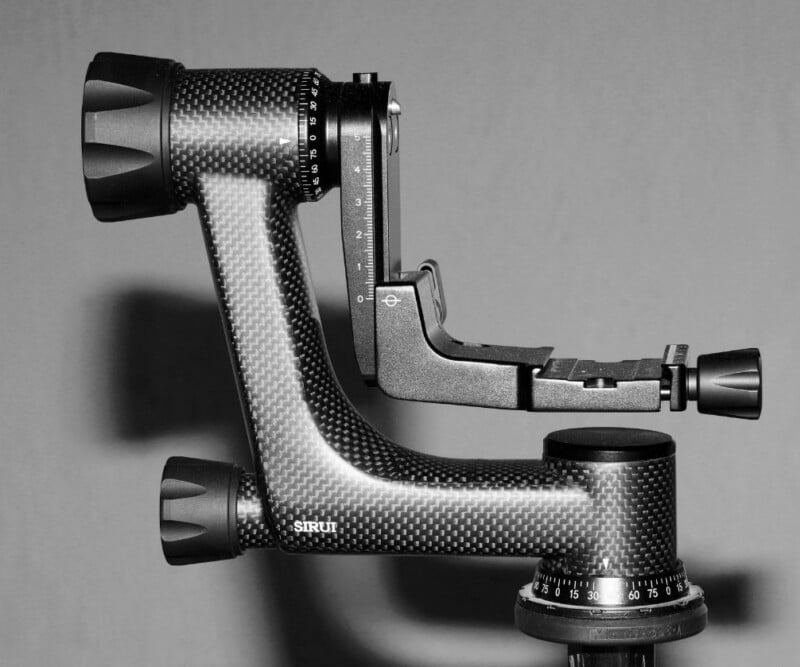 A carbon-fiber gimbal head stands against a gray background. It features adjustable knobs and a mounting plate designed for precise camera positioning, ideal for photography.