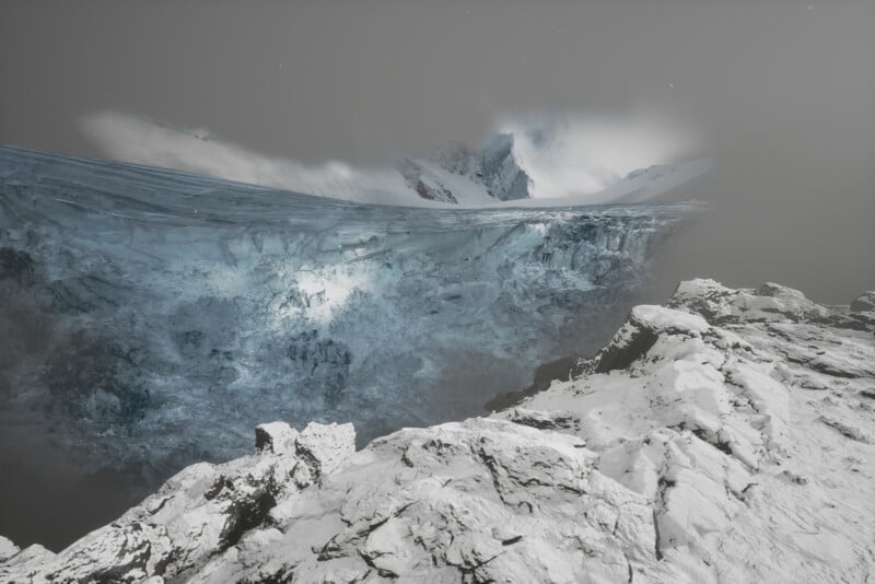 A vast, icy landscape features a large glacier under a gray, cloudy sky. Snow-covered rocky terrain is in the foreground, with towering, jagged mountains partially obscured by mist in the background.