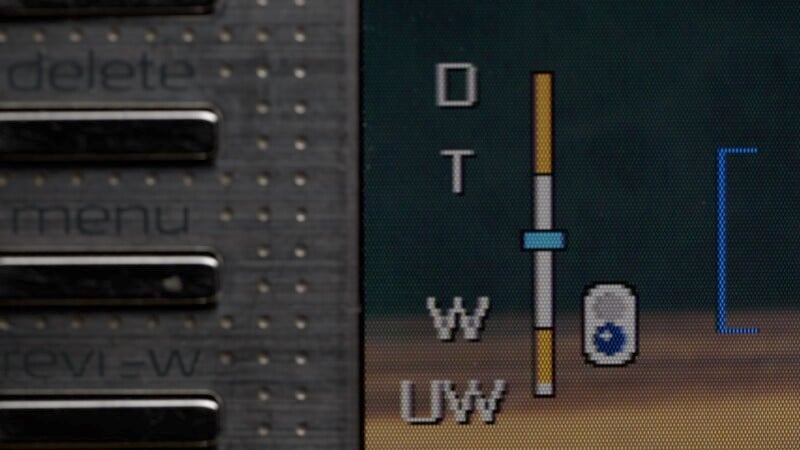 Close-up of a screen displaying a vertical bar with adjustable markers labeled with letters on the right. Part of a textured side panel with buttons labeled delete, menu, and revi-W is visible on the left.