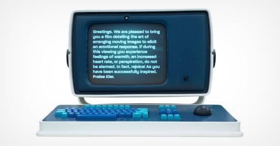 A retro-style computer with a blue screen displays text about film-induced emotional responses. The computer features a blue and teal keyboard and a joystick, evoking a vintage aesthetic.