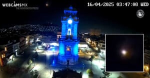 A nighttime view of a blue-lit clock tower in a city plaza, with a bright light in the sky. The date reads 16/04/2025 at 03:47. An inset shows a close-up of the glowing object in the night sky.