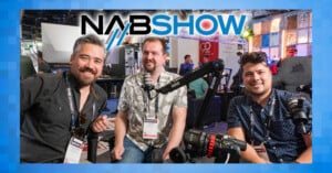 Three people are sitting and smiling at the NAB Show, surrounded by audio equipment, including microphones. The event logo is prominently displayed at the top. The background features a lively exhibition setting.