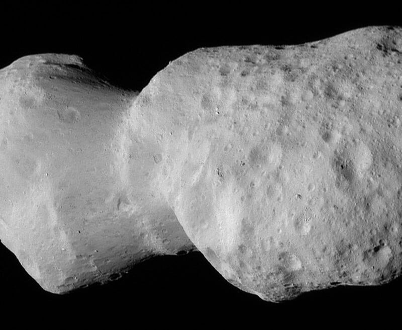 Close-up image of a gray, irregularly shaped asteroid with a bumpy, cratered surface, floating against the blackness of space.