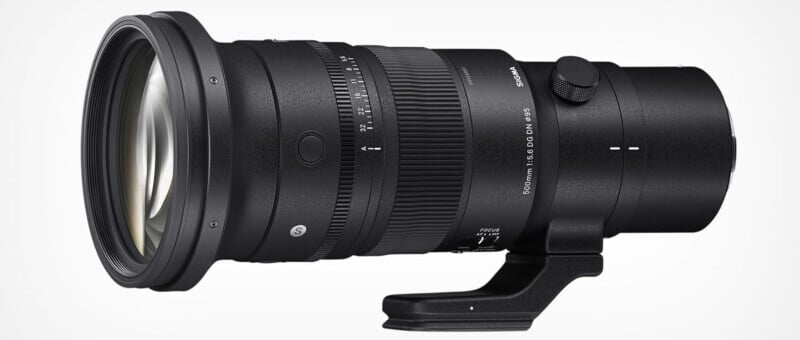 A black camera telephoto lens with a focus ring and distance markings. It has a tripod mount foot and is designed for high zoom and professional photography. The lens is identifiable by its brand logo on the side.