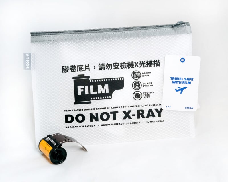 A clear mesh pouch labeled "FILM DO NOT X-RAY" in multiple languages, with film icons and a warning. A roll of 35mm film is partly out of the bag, and a tag reads "TRAVEL SAFE WITH FILM.