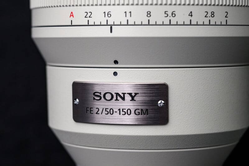 Close-up of a Sony camera lens with a metallic label reading "SONY FE 2/50-150 GM" and a focus or aperture scale above it, set against a black background.