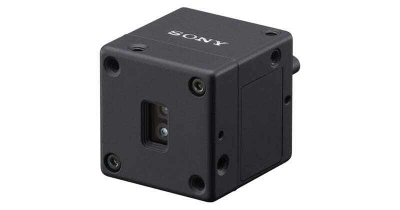A small, black, cube-shaped Sony camera with a lens on one side and the Sony logo on the top, featuring multiple screw holes and a minimalist industrial design.