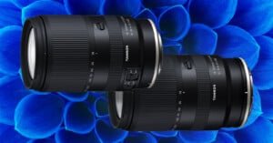 Two black Tamron camera lenses are displayed diagonally against a vibrant blue petal-like patterned background. The lenses show detailed markings and branding.