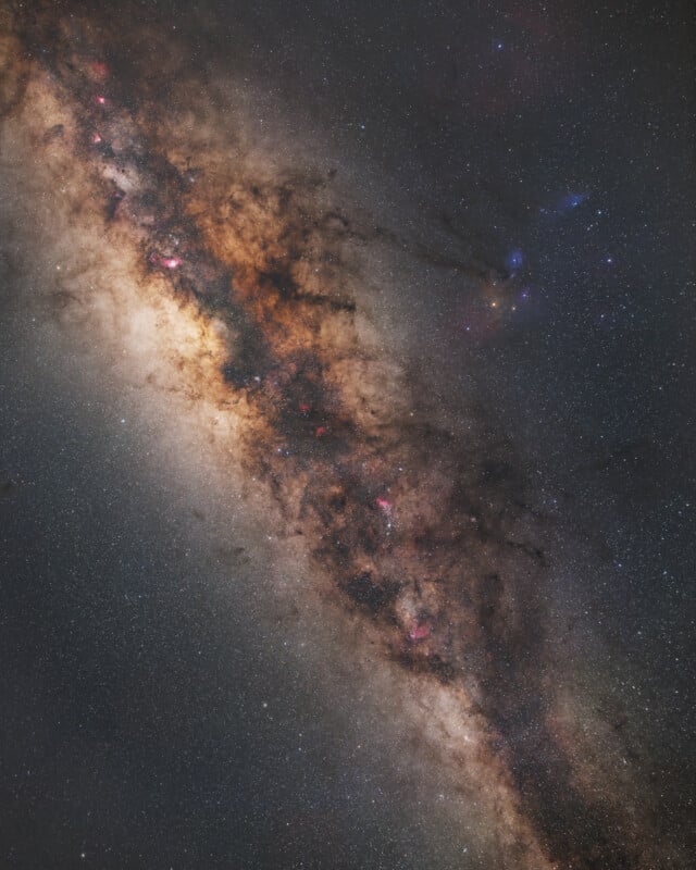 A detailed view of the Milky Way galaxy’s core, showing dense clouds of stars, bright dust lanes, and colorful nebulae against a dark, star-filled background.