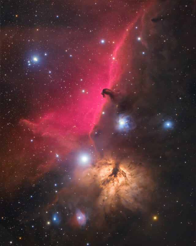 Colorful deep-space image showing the Horsehead Nebula and bright stars, with glowing red and orange clouds of gas, dust, and scattered blue and white highlights against a backdrop of countless stars.