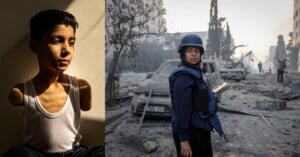 A boy with amputated arms sits in shadow on the left; on the right, a journalist in a helmet and vest stands amid rubble and destroyed cars in a war-torn urban area.